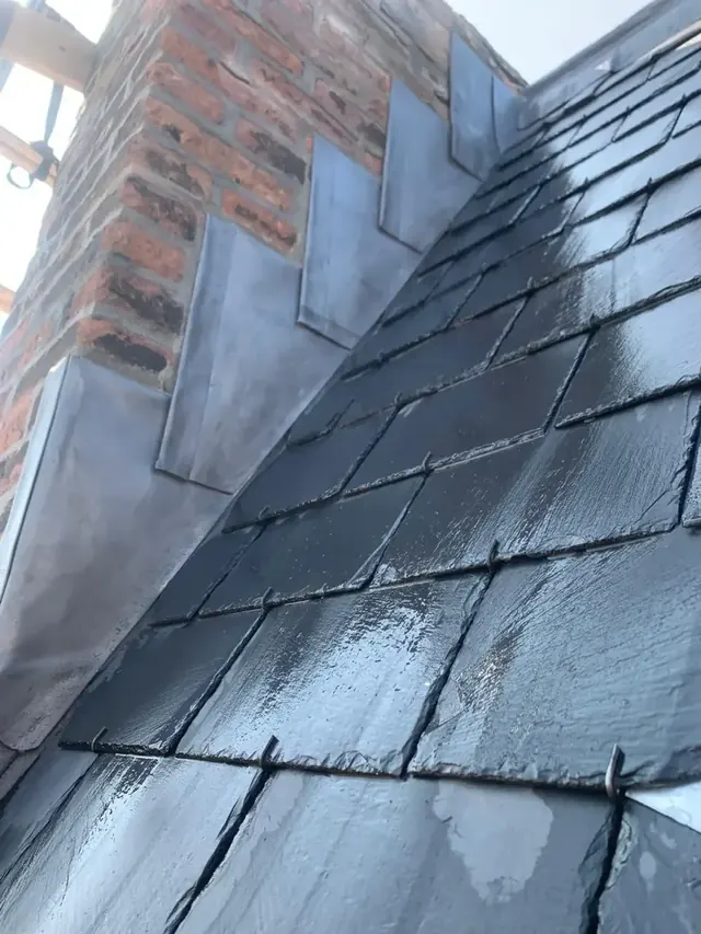 Loodslabben boven leien — Loodwerk sluit het leien dak aan op het metselwerk van de gevel.